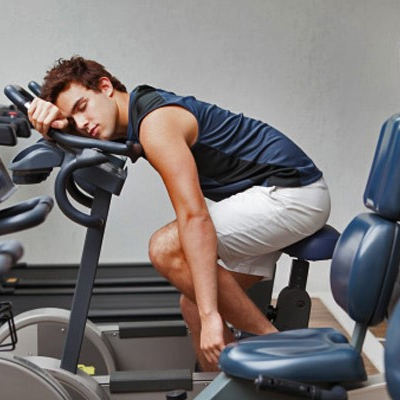 a man falling asleep on a bike in the gym